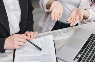 Mani di persone su una scrivania con un computer e un contratto