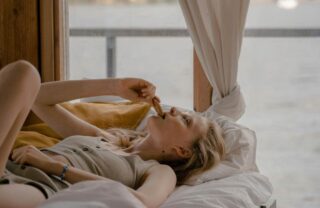 Donna stesa sul letto che mangia un biscotto