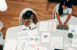 Donne sedute a una scrivania, con grafici e laptop