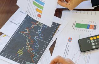 Una scrivania con vari documenti, fra cui grafici e report