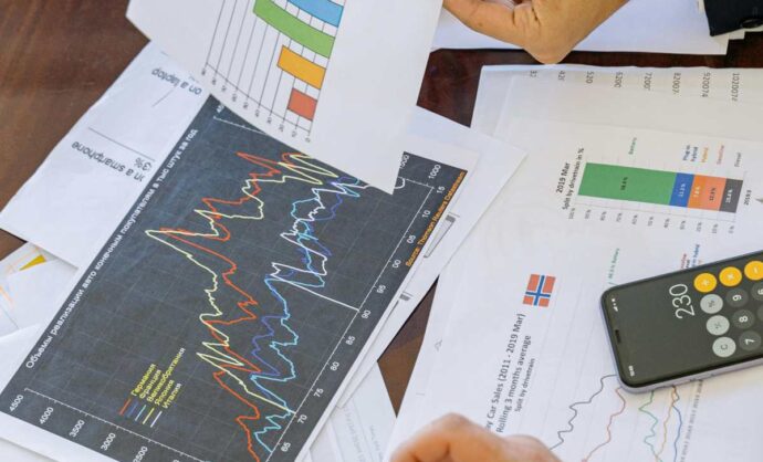 Una scrivania con vari documenti, fra cui grafici e report