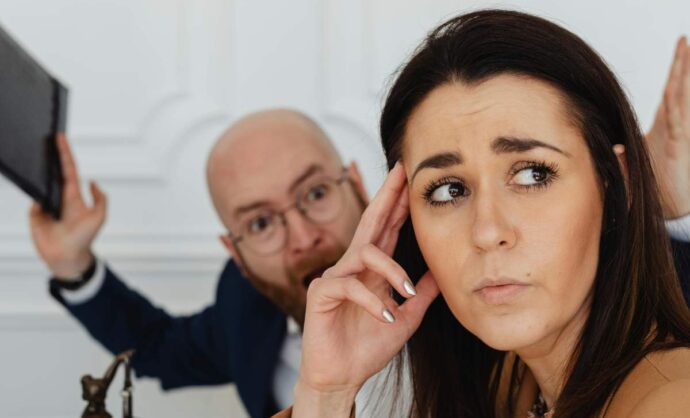 Donna stressata con alle spalle un uomo che grida