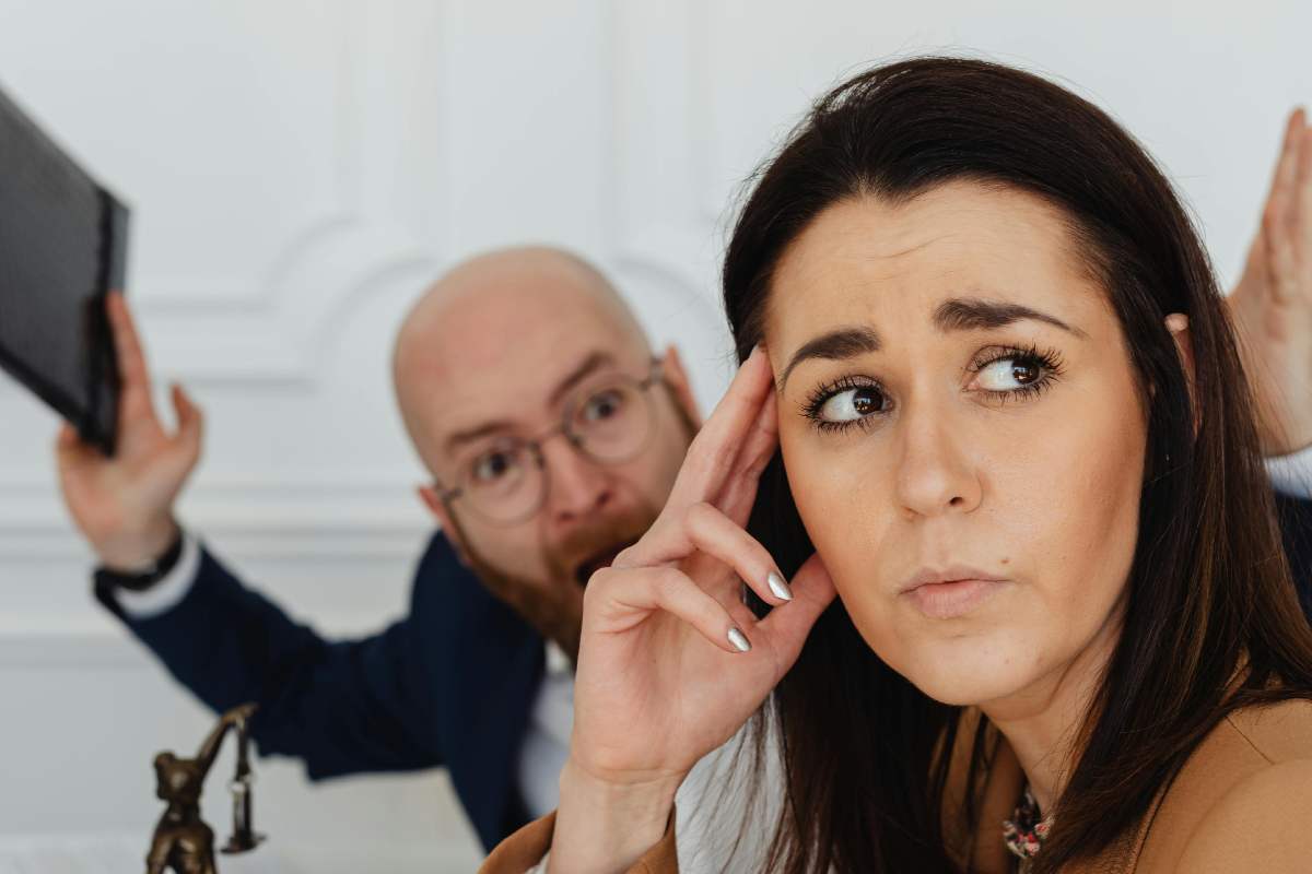 Donna stressata con alle spalle un uomo che grida