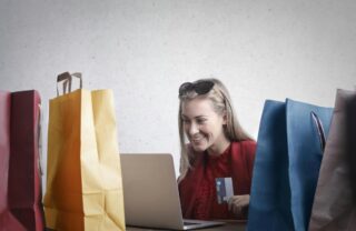 Ragazza che fa acquisti al pc circondata da buste
