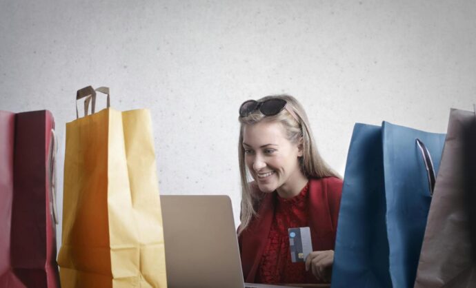 Ragazza che fa acquisti al pc circondata da buste