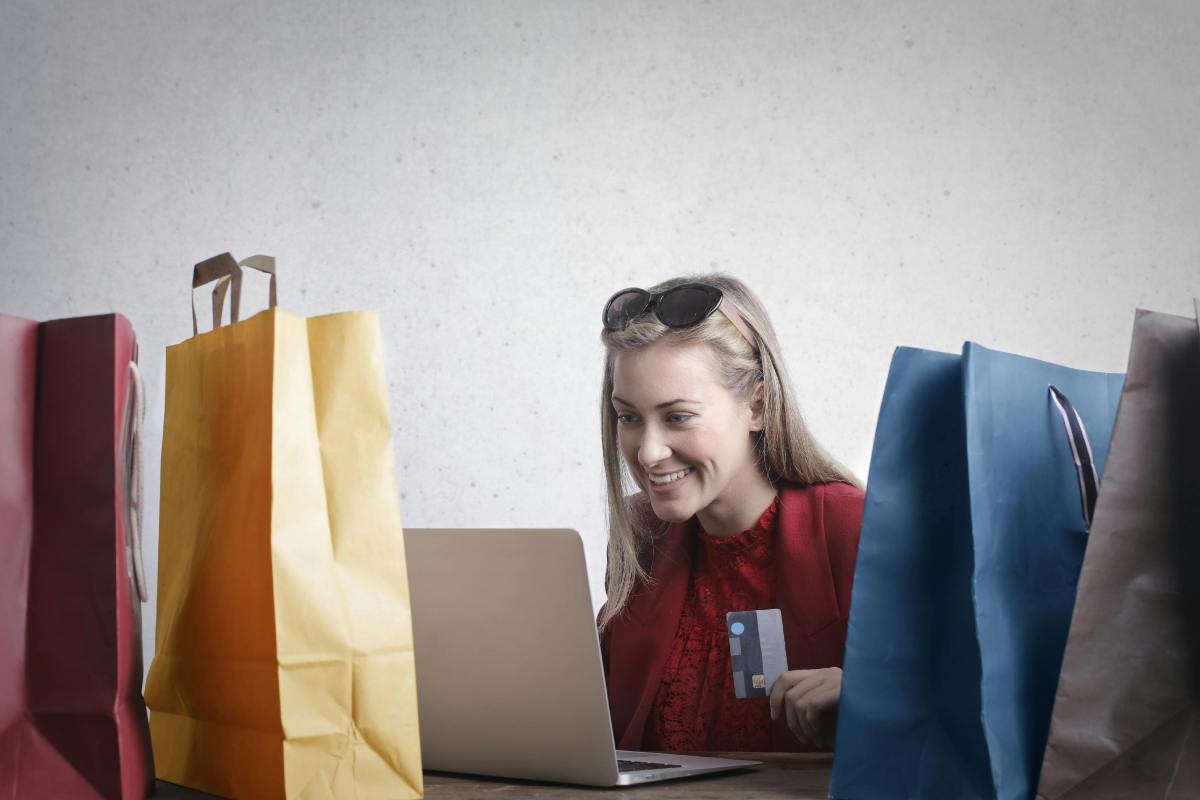 Ragazza che fa acquisti al pc circondata da buste