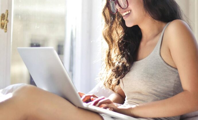 Ragazza stesa a letto che usa il laptop