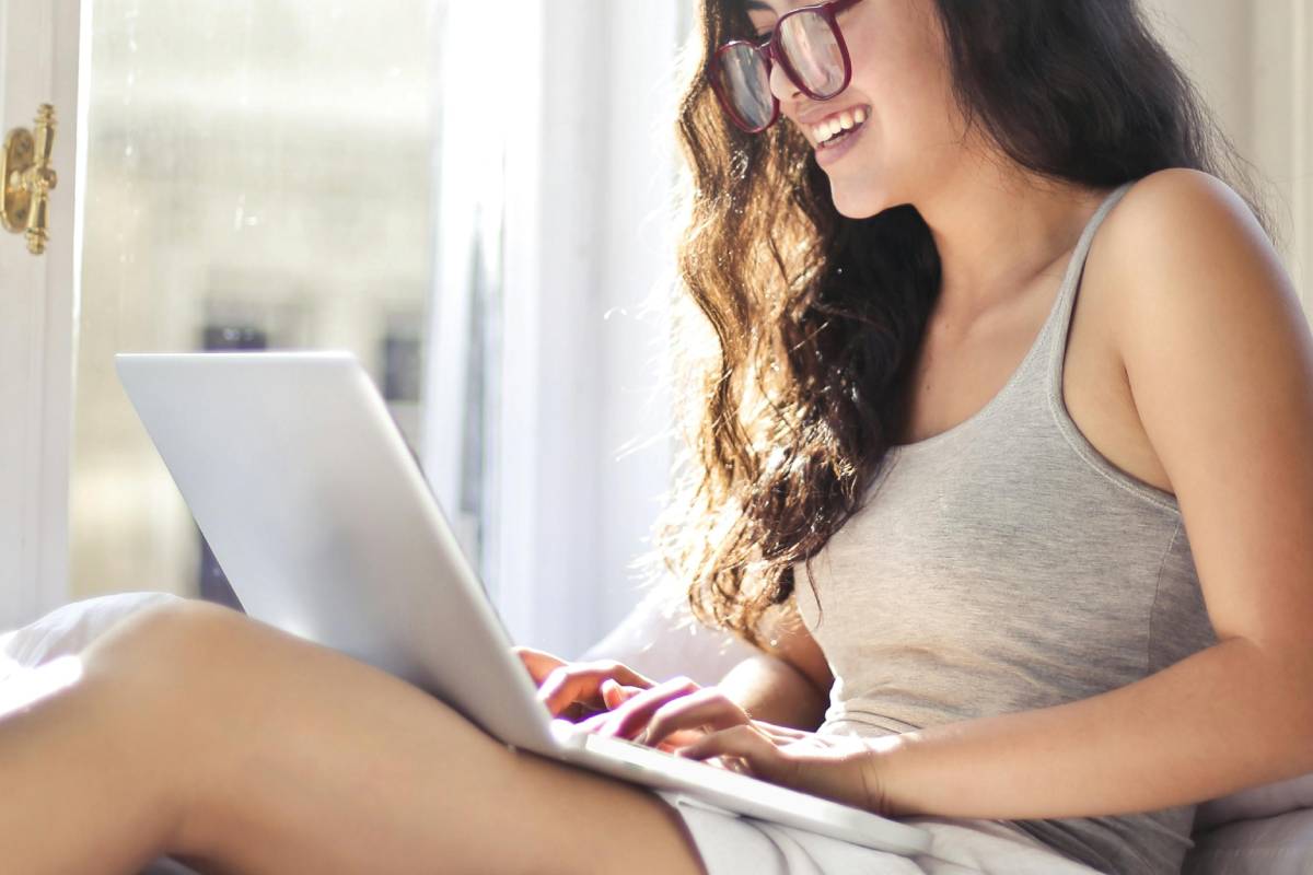 Ragazza stesa a letto che usa il laptop