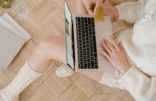 Ragazza che compra online con un portatile sulle gambe
