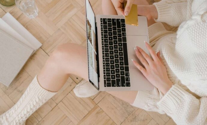 Ragazza che compra online con un portatile sulle gambe