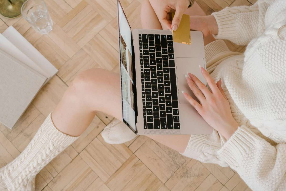Ragazza che compra online con un portatile sulle gambe