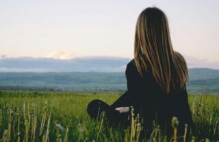 Ragazza seduta sull'erba che guarda l'orizzonte