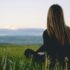 Ragazza seduta sull'erba che guarda l'orizzonte