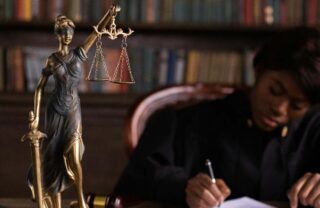 Giudice al lavoro sulla scrivania con statuetta della personificazione della Giustizia
