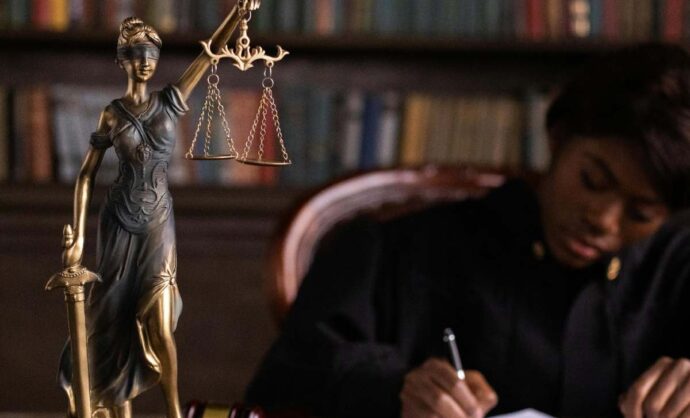 Giudice al lavoro sulla scrivania con statuetta della personificazione della Giustizia