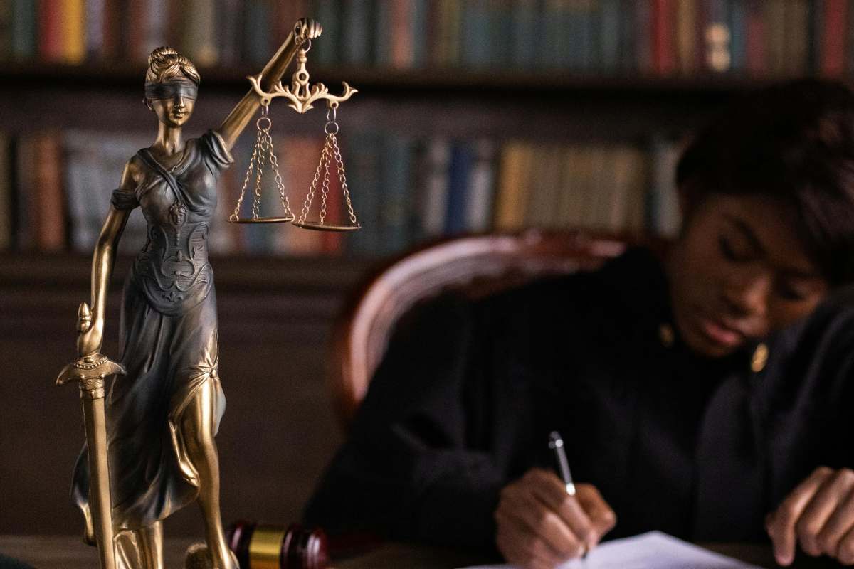 Giudice al lavoro sulla scrivania con statuetta della personificazione della Giustizia
