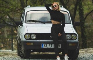 Ragazza in posa davanti a una vecchia Renault