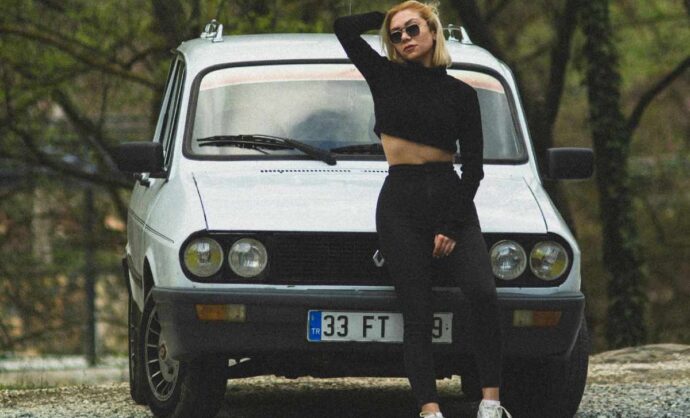 Ragazza in posa davanti a una vecchia Renault