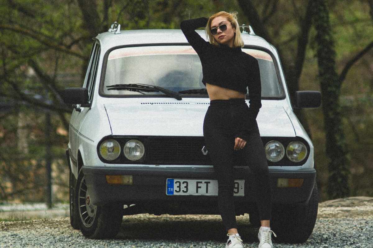 Ragazza in posa davanti a una vecchia Renault
