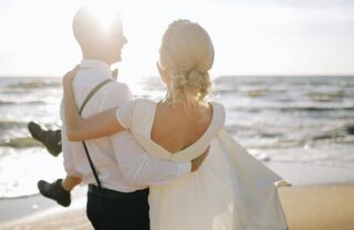 Sposa in braccio allo sposo sulla spiaggia