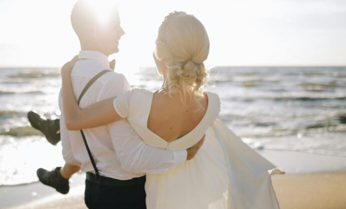 Sposa in braccio allo sposo sulla spiaggia