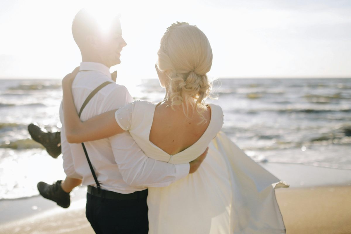Sposa in braccio allo sposo sulla spiaggia
