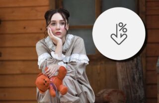 Ragazza seduta fuori da una casa di legno e, in evidenza, una percentuale in calo